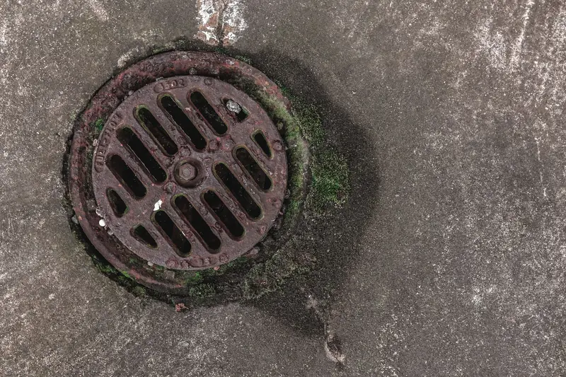 A round cast-iron drain grating set into the ground outside