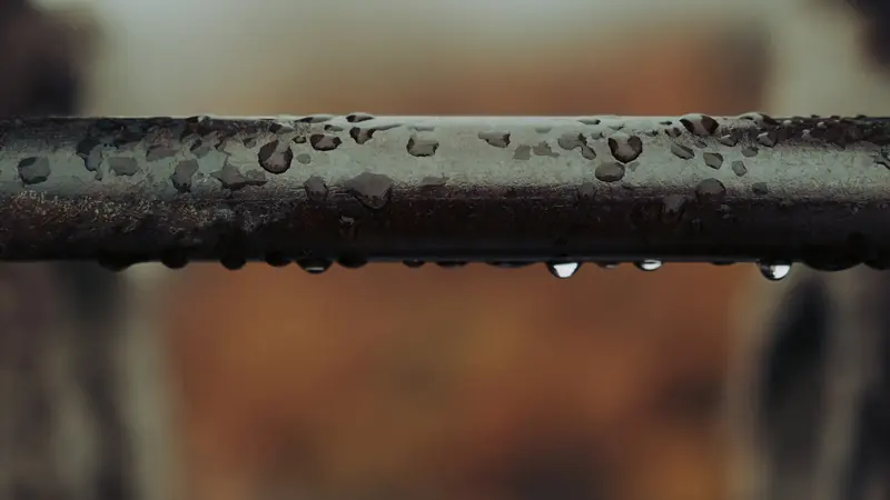 Drops of water gathering along the underside of a pipe