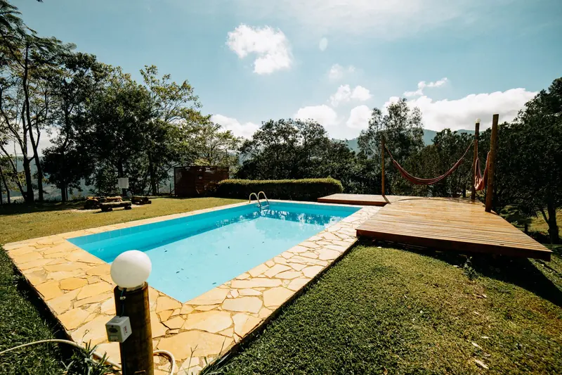A rectangular swimming pool on a lawn with a timber deck