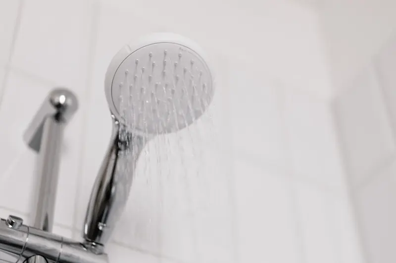 A shower head running with only a few thin streams of water