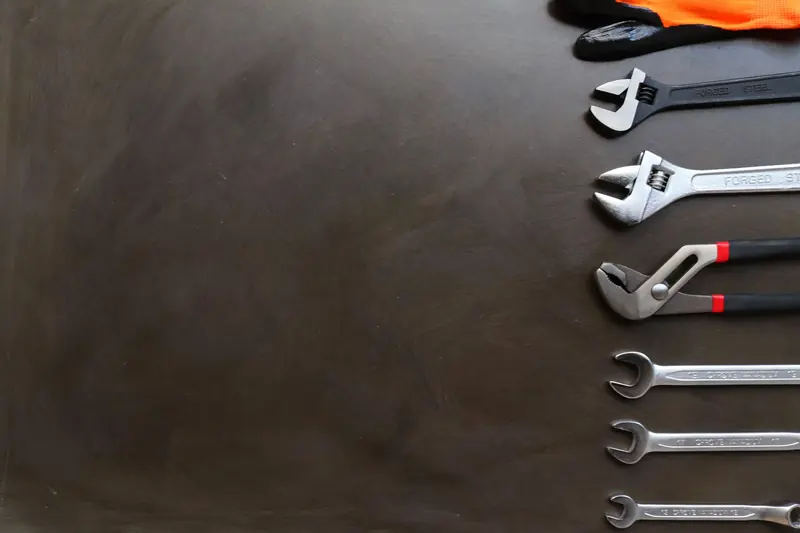 Pipe wrenches and spanners laid out on a dark workbench